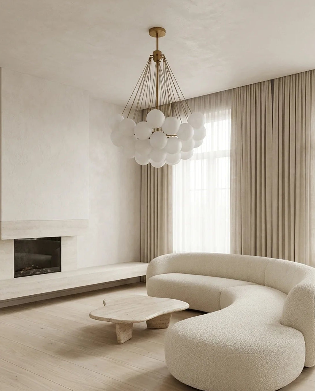 A modern curved cream bouclé sofa in a minimalist, light beige living room with a matching low wooden coffee table and a distinctive spherical glass chandelier.